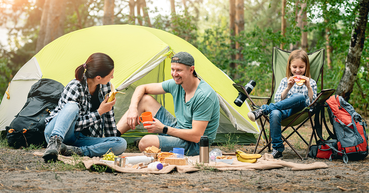 A family enjoys a picnic while tent camping.