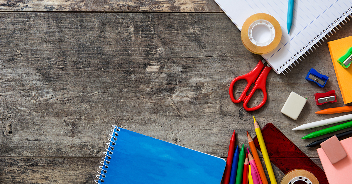 An assortment of colorful back-to-school supplies spread out on a wooden table.