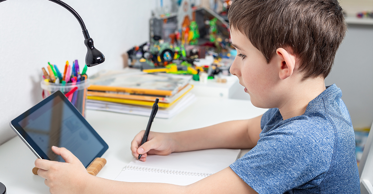 A young boy does homework with the aid of an educational app on a tablet.