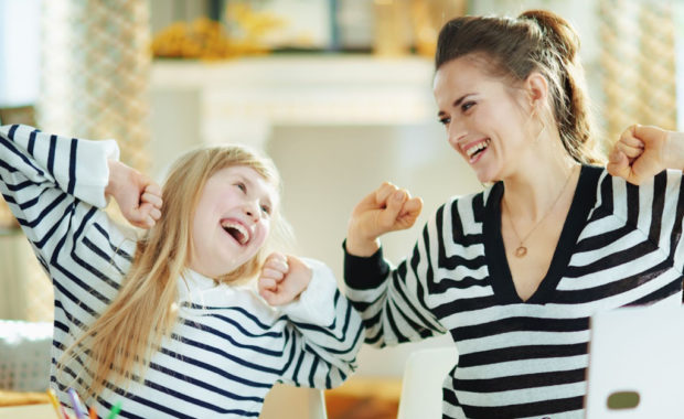 A child and parent cheer while homeschooling.