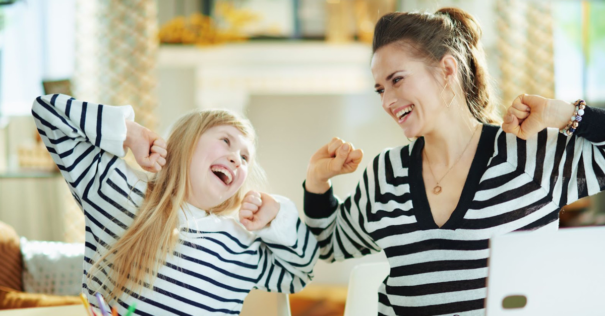 A child and parent smile and cheer while homeschooling.