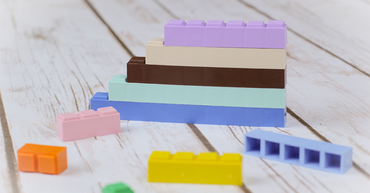 Colorful Math-U-See manipulatives stacked and scattered on a white, wooden table.