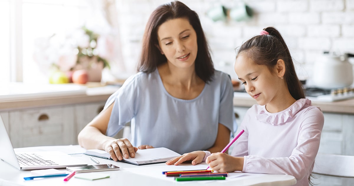 A mother and daughter sitting at a table doing schoolwork.