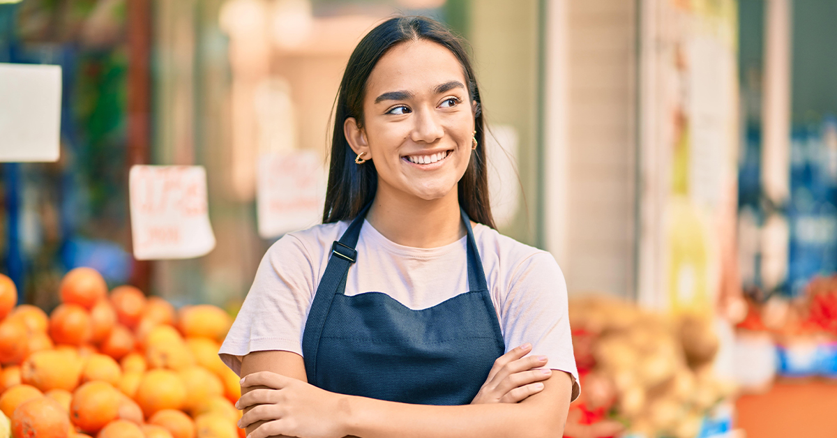 Teenage girl wearing an apron while working at a produce stand.