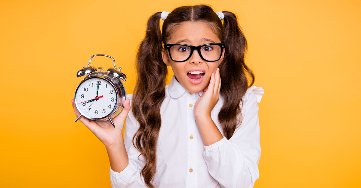 Young girl looks worried while holding up a clock.