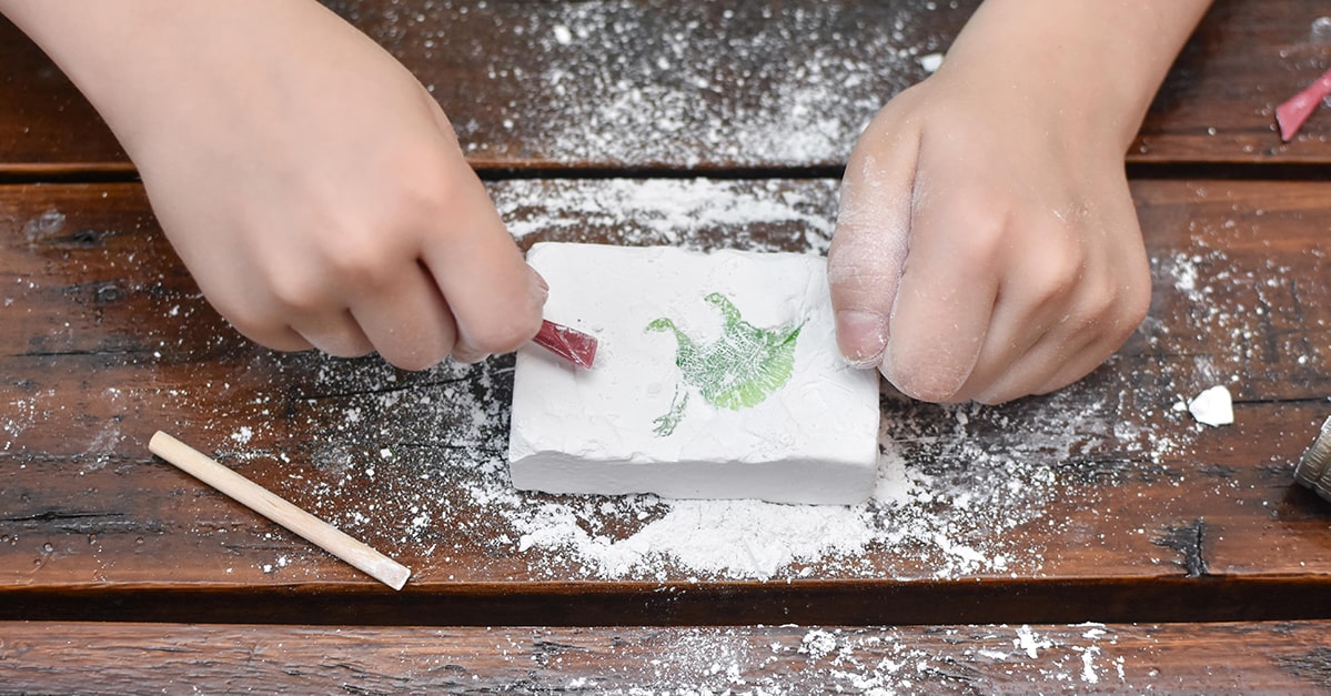 Child carves a fossil out of a model archeologist  kit.