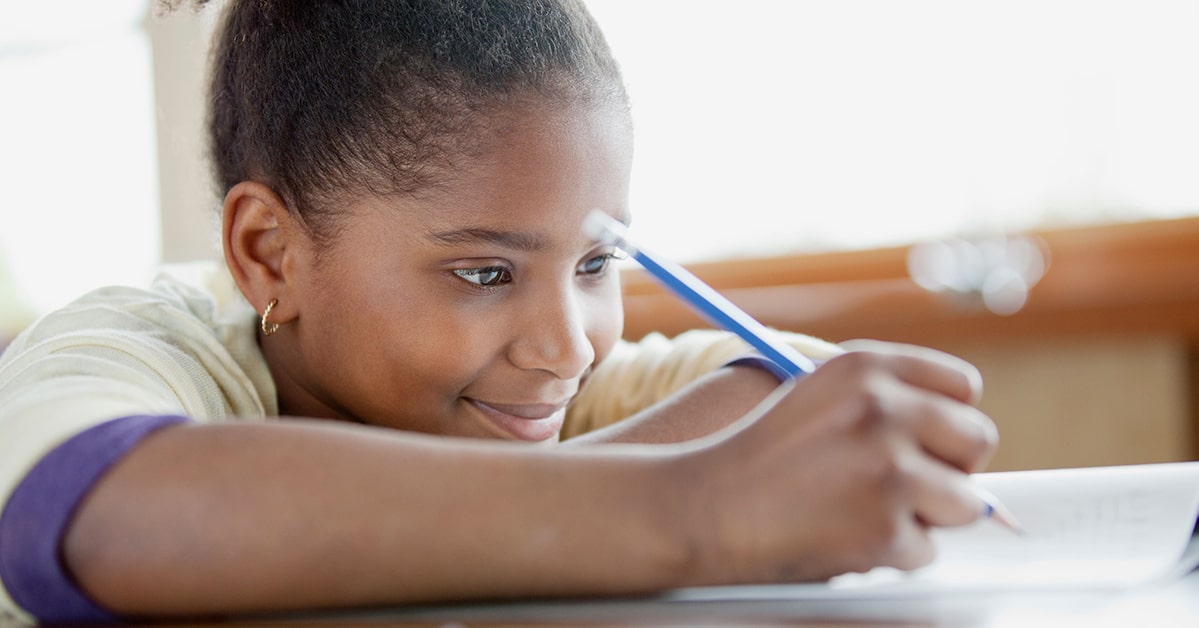 Young girl smiles as she writes in a journal.