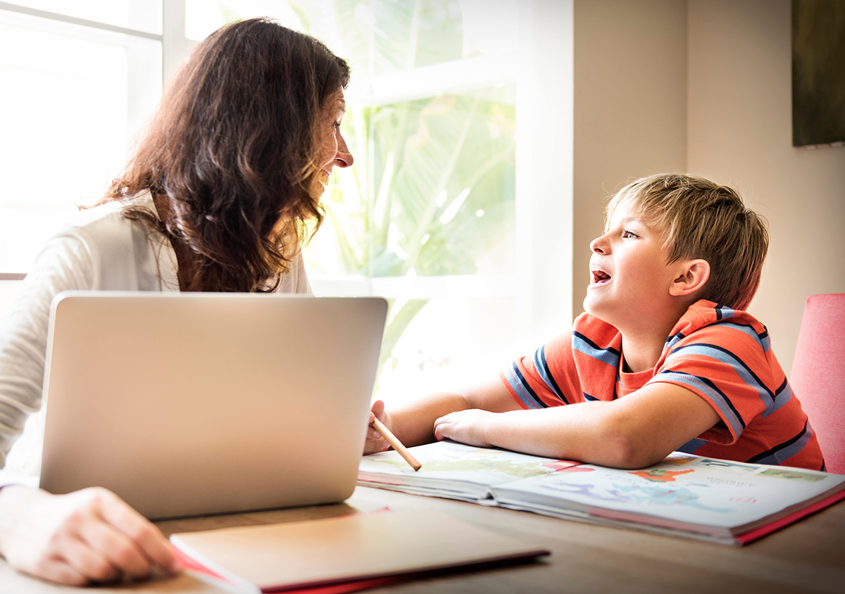 A woman and a young boy work together at a table.