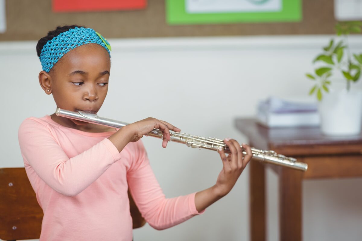 Alt text: A young girl practices playing the flute.
