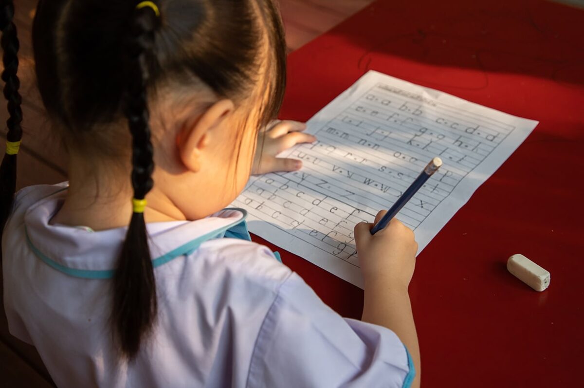 Little girl practicing lower case letter formation.