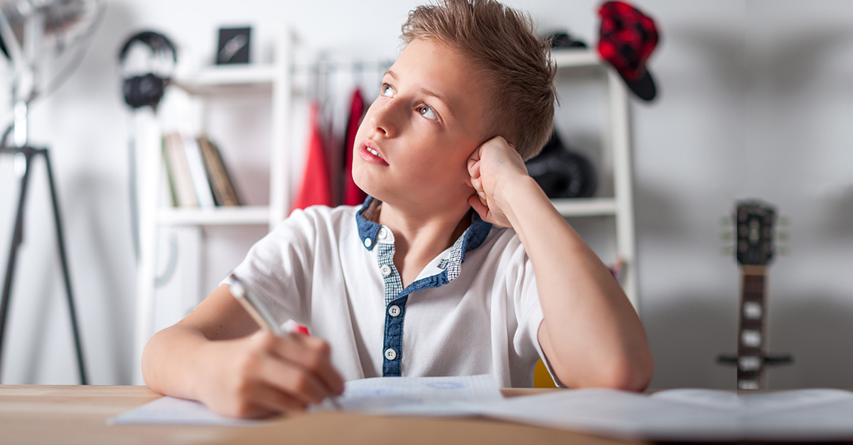 A young boy thinks while doing homework.