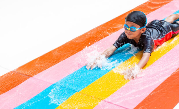 A young boy goes down a water slide.