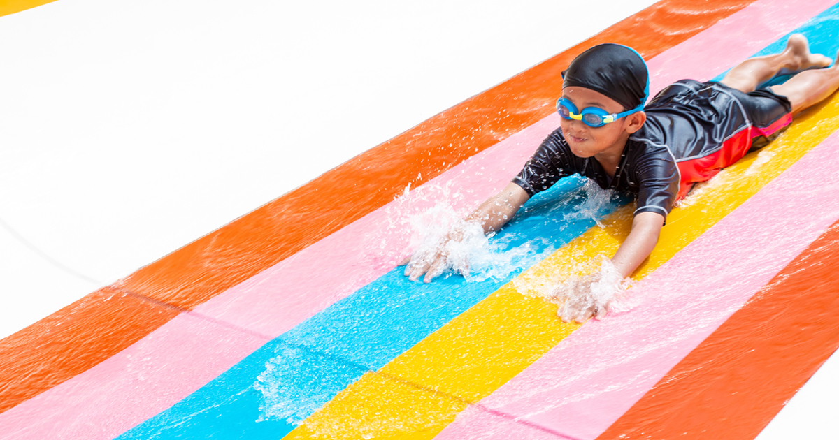 A young boy goes down a water slide.