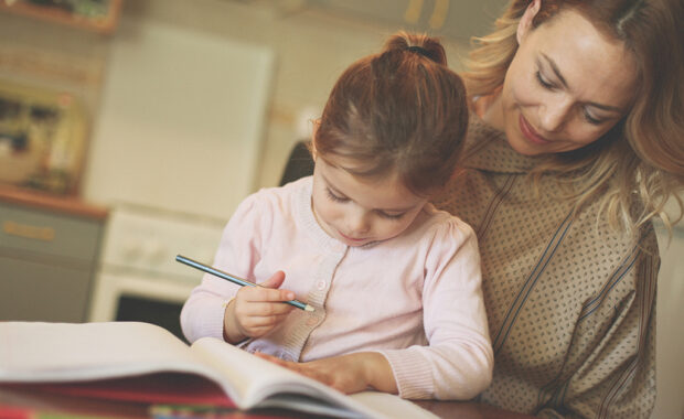 A young girl and her mother work on homework together.