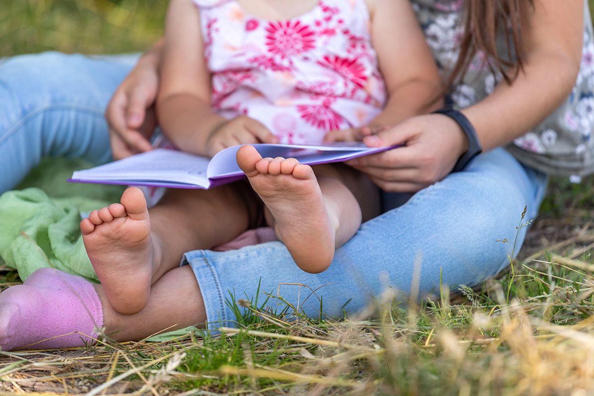 Two people reading a book outside.