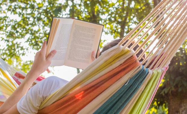Someone reading a book in a hammock.