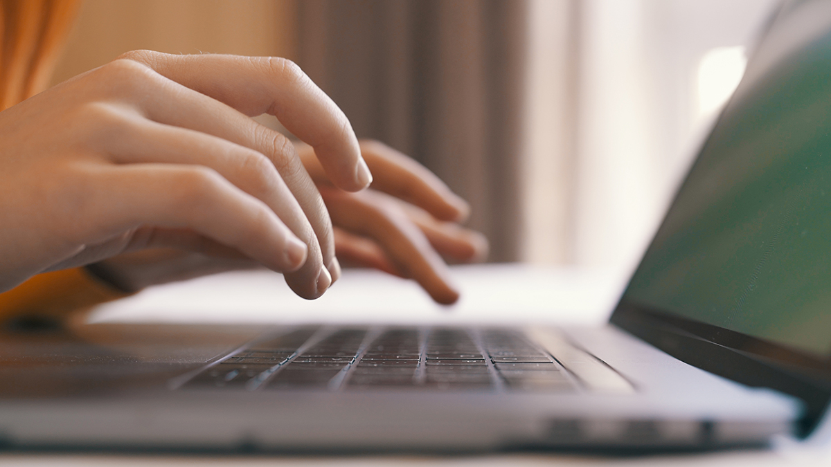 A college students types on a laptop keyboard.