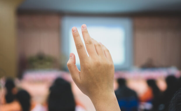 A college student raises their hand during class.