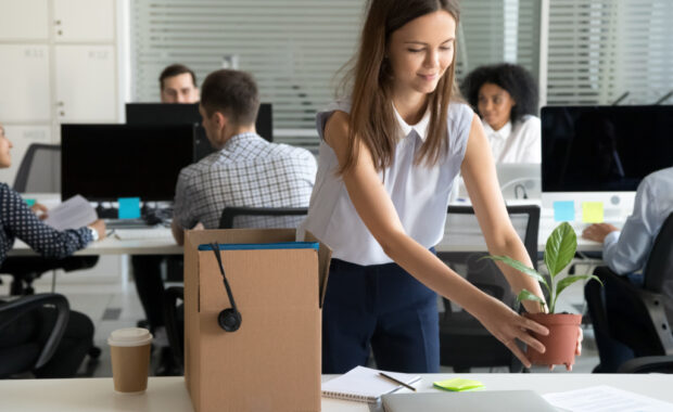 A young woman puts a plant down at her workstation.