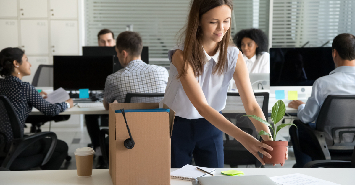 A young woman puts a plant down at her workstation.