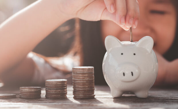 A child puts money in their piggy hank