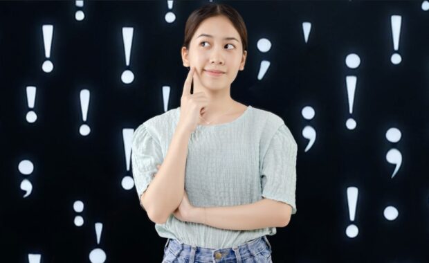 A student standing in front of illustrations of punctuation marks