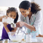 A mother and daughter mixing ingredients together
