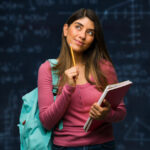 A math student poses in front of a chalkboard