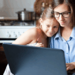 A mother and daughter working on a laptop together