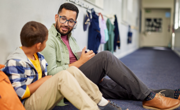 A teacher sitting with a student and talking to them