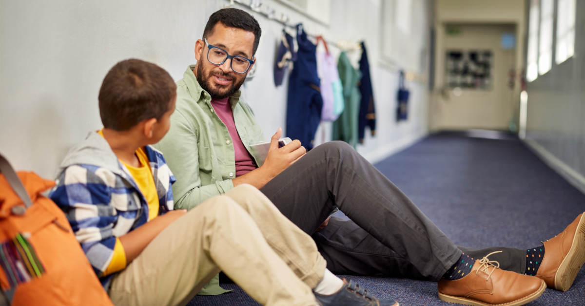 A teacher sitting with a student and talking to them